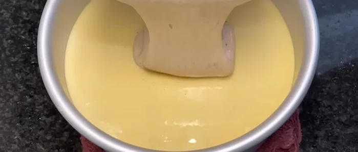 Pour the cocoa batter over the custard in the mold.
