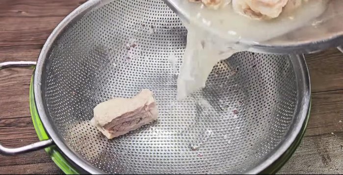Drain the boiled ribs in a basket.