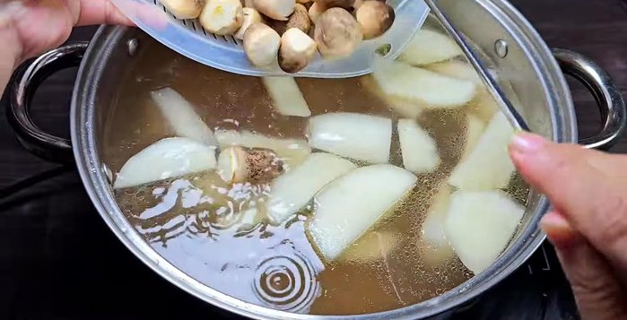 Add mushrooms and carrots: After resting, heat the broth again. Add straw mushrooms and simmer for 10 minutes. Then add carrots and simmer for another 10 minutes.