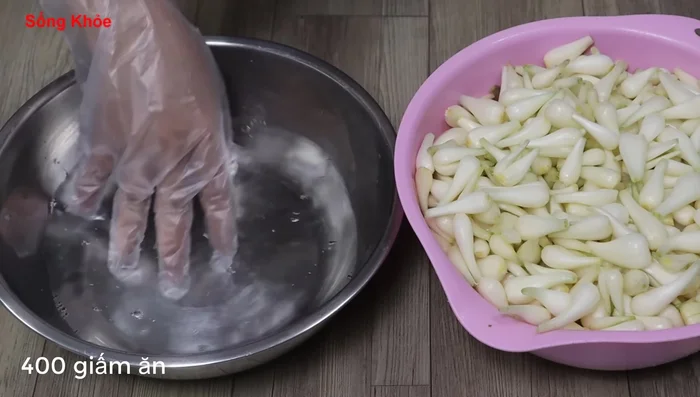 Prepare the vinegar water (400ml vinegar). Briefly rinse the Kiệu in vinegar water to clean them.