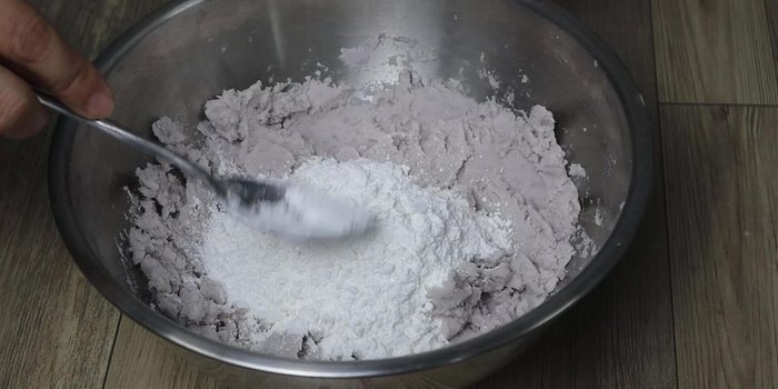 Gradually add sticky rice flour (or tapioca starch) and boiling water to the mashed taro, mixing to form a soft dough.