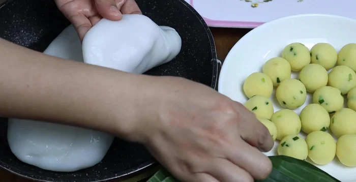 Take a small portion of the tapioca dough, wrap a filling ball inside, and pinch to seal. You can use banana leaves to wrap the dumplings for steaming.