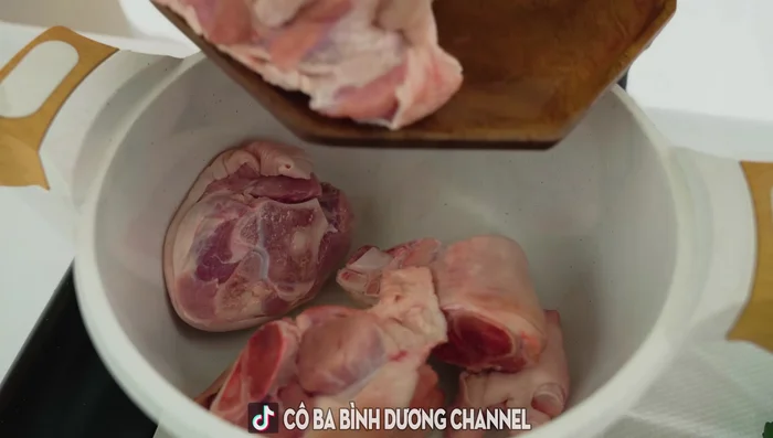 Clean the pig's trotters by soaking and washing them with salt and vinegar. Then, boil them for 1-2 minutes with water, crushed ginger, salt, and white wine or vinegar to remove the pork smell. Immediately soak in cold water to keep the ham white and skin firm.