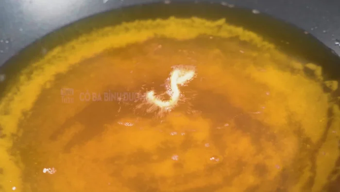 Fry the pork leg, continuously basting with oil to ensure even crispiness.
