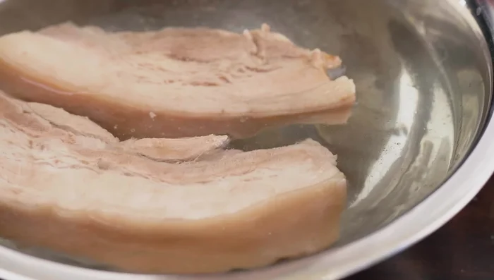 Once the pork is cooked, remove and immediately place in cold water to prevent discoloration. Wash the meat twice to remove fat and foam.