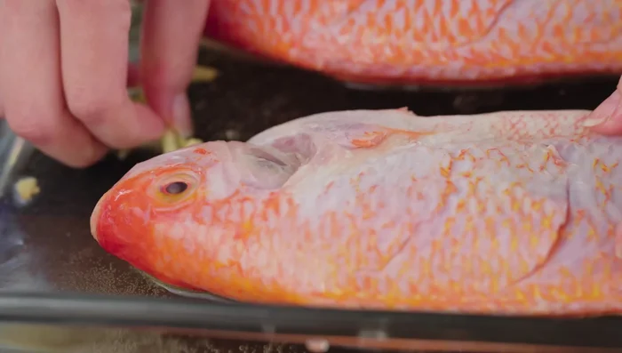 Place the fish in a basin, add ginger, 250ml of beer, and a little salt. Rub the mixture evenly onto the fish to remove the fishy smell, paying attention to the belly, gills, and slits.