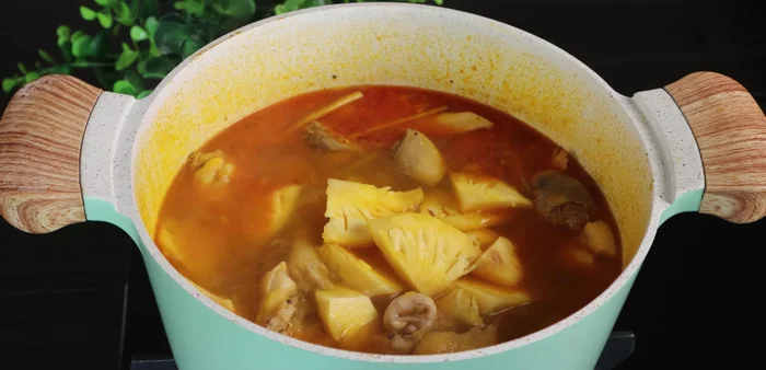 After 10 minutes, add the pineapple. Cook until the chicken is tender. Then add the carrots, black fungus, and straw mushrooms. Cover and cook for another 5 minutes.