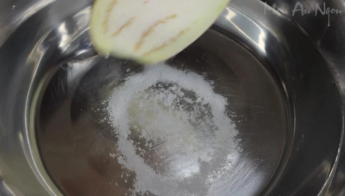 Place eggplant halves in a basin of water with 1 tablespoon of salt to prevent browning. Submerge the flesh to keep it from turning black. (39.399)