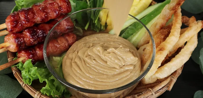 Serve with grilled spring rolls, raw vegetables (cucumber, pineapple), crispy fried rice paper, and ground chili to taste.