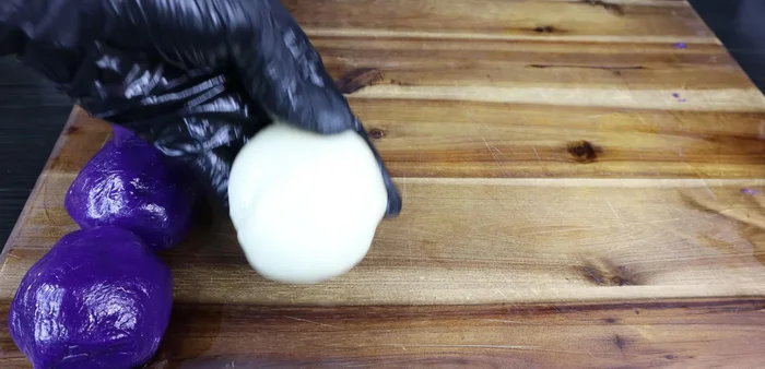 Assemble the mooncakes: Divide the dough, Mochi filling, salted egg yolk filling, and taro filling into equal portions. Layer the fillings (Mochi, salted egg yolk, taro) inside the dough and form into balls.
