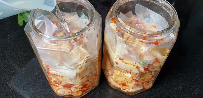 Pour the cooled salt-sugar water mixture into the jars, ensuring the bamboo shoots are fully submerged. Use a plastic bag to weigh down the shoots and prevent discoloration.