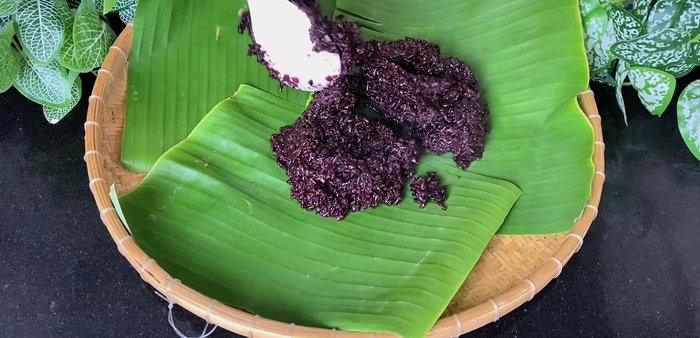 Spread the cooked sticky rice evenly on a tray lined with a banana leaf to cool (218.239).
