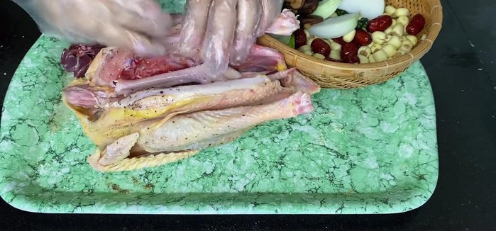 Stuff the chicken cavity with green onion roots, shiitake mushrooms, lotus seeds, and Chinese dates. Pack it firmly.