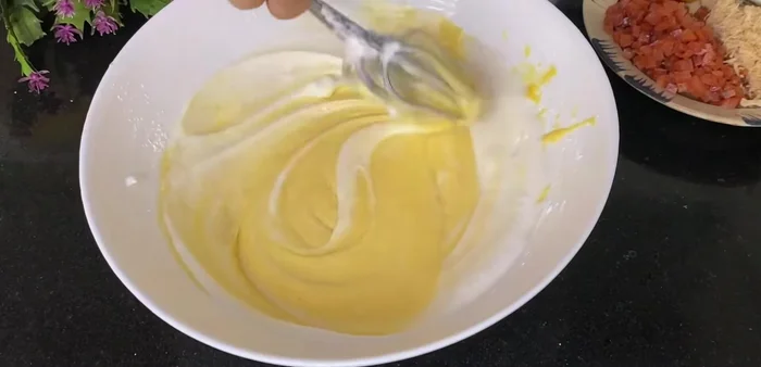 Combine yolk and egg white mixtures: Gently fold 1/3 of the beaten egg whites into the yolk mixture to lighten it. Then, gently fold the remaining egg whites into the yolk mixture until just combined. Avoid overmixing.