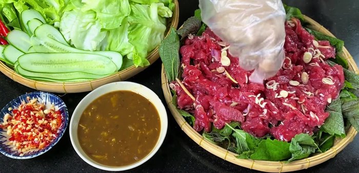 Arrange the beef and vegetables on a steamer tray: Layer perilla leaves, then add the marinated beef, lemongrass, and ginger. Add more perilla leaves on top.