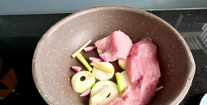 Place the pork pieces on top of the aromatics. Cook over low heat until the meat is cooked and the water has evaporated.