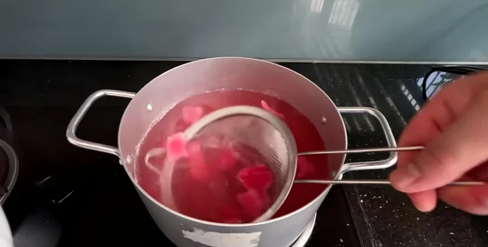 Remove dragon fruit peels from the pink jelly mixture after cooking.