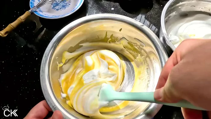 Gently fold 1/4 of the beaten egg whites into the yolk mixture to lighten it. [226.319]