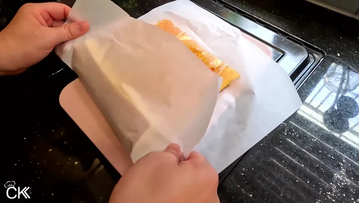 Roll up the cake tightly using the parchment paper as a guide. [439.24]