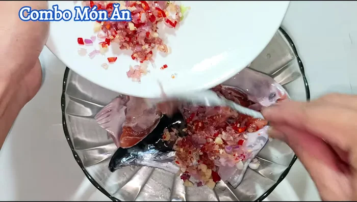 Marinate the salmon head with half of the chopped garlic, shallots, chili, sugar, sweet soy sauce, seasoning powder, ground pepper, fish sauce, and caramel. Let it marinate for 15 minutes.