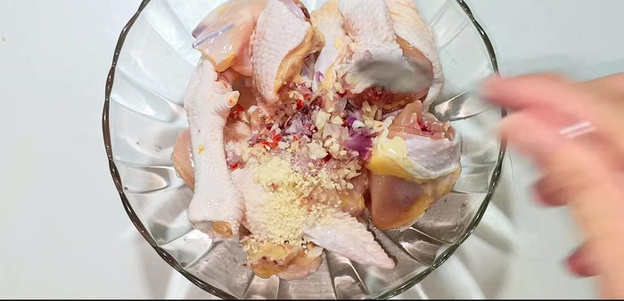 Marinate chicken with half of the chopped garlic, chili, shallots, seasoning powder, MSG, sugar, water, fish sauce, oyster sauce, chili sauce, and shrimp satay. Marinate for 20-25 minutes.
