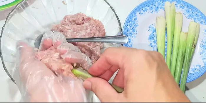Wrap the marinated pork around the lemongrass stalks, ensuring the meat is tightly packed.