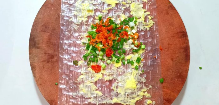 Add a small amount of green onions, sausage, and quail egg to each rice paper. Spread evenly with a spoon.