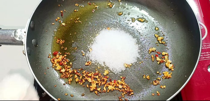 Add sugar, MSG, ground pepper, water, fish sauce, soy sauce, and dried chili powder to the pan. Stir well to dissolve the spices.