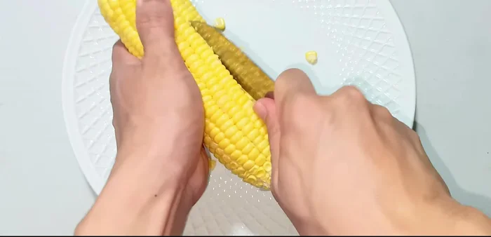 Separate the corn kernels from the cob using a knife and your hands. Gently squeeze the kernels to separate them.
