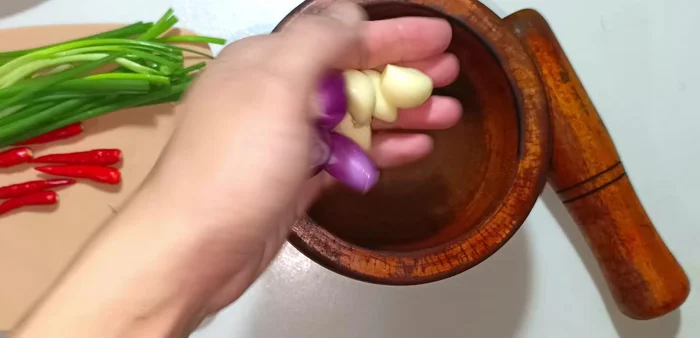 Pound garlic, shallots, and 3 chili peppers together.