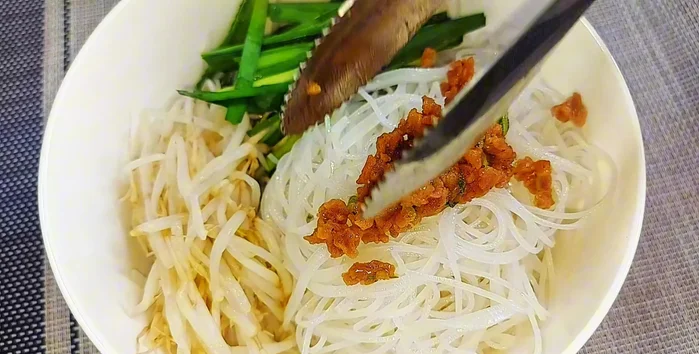 Assemble the noodles: Put noodles, bean sprouts, chives, and toppings in a bowl. Add soup and a little water. Mix.