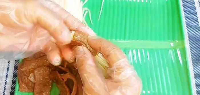 Take an enoki mushroom bunch and wrap it with a portion of the vegetarian beef mixture. Secure with a bamboo skewer.