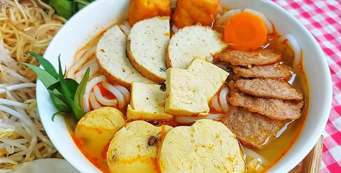 Soak and wash the vegetarian beef until soft. Prepare other ingredients like fried tofu, white tofu, vegetarian sausages, and vegetables (carrots, white cabbage, pickled cabbage, squash).