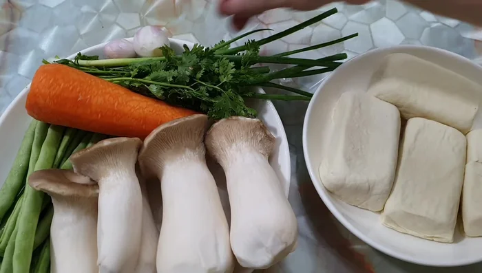 Prepare ingredients: 4 blocks of white beans, 300 grams of chicken thigh mushrooms, peas, carrots, green onion, and coriander.