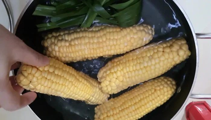 Add the corn and pandan leaves to the boiling water.