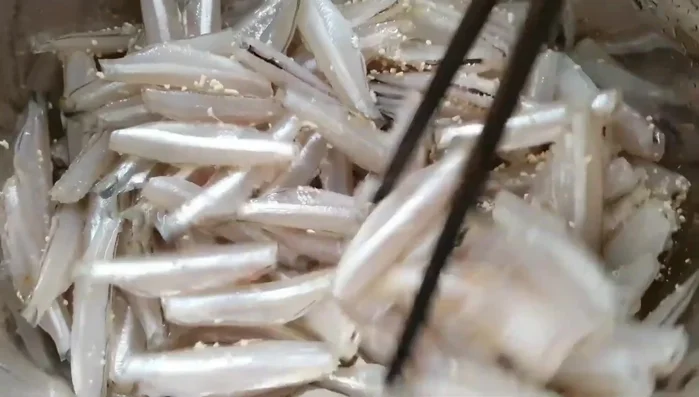 Clean and prepare the anchovies. Remove the fishy smell by washing and draining them. Add white wine to further reduce the odor.