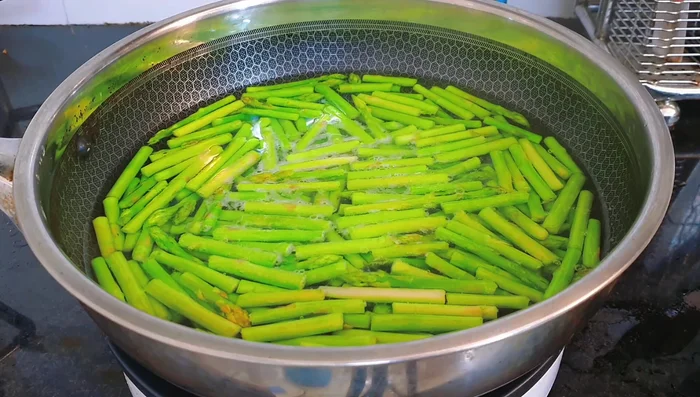 Immediately transfer blanched asparagus to ice water for 2 minutes to retain its green color and crispness.