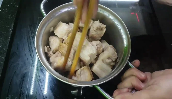 Add the pre-boiled pork belly, cut into large pieces, to the caramel mixture.