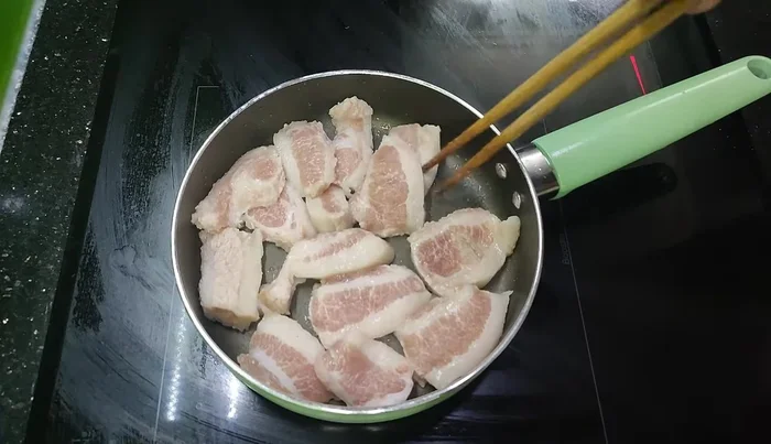 Add the meat to the hot pan and press it down to release the fat. Cook until crispy and golden brown.