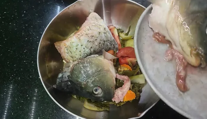 Place the prepared fish head and tail on top of the tomatoes.
