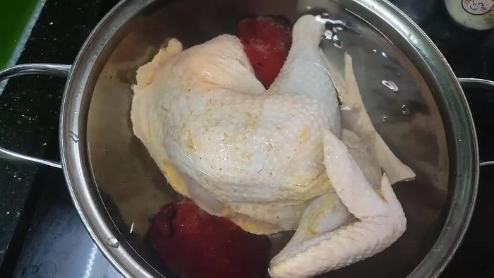 While the chicken is boiling, thinly slice green onions, chili, and kumquat. Prepare more onions and also cut the chicken into thin slices.