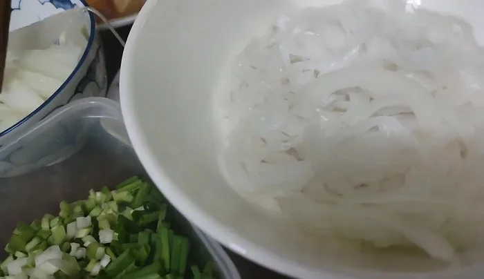 Prepare the bowls. For adults, add thinly sliced onions, spring onions, and green onions. For children, only add green onions.