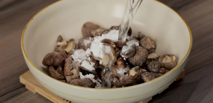 Soak shiitake mushrooms in water with tapioca starch for 15-20 minutes to clean and remove musty smell. Use a plate to submerge them completely.