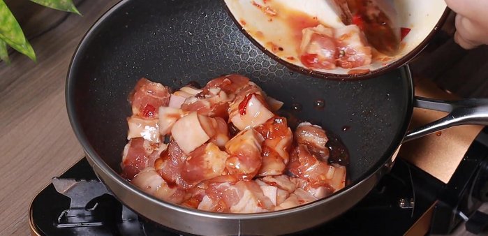 Add the marinated pork to the pan and stir-fry until the caramel color is absorbed into the meat.