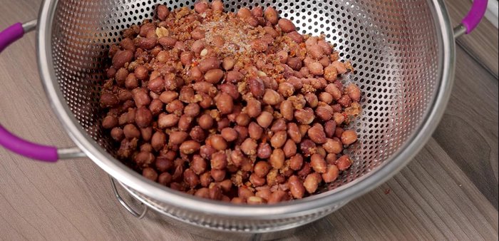 Once cooled, transfer peanuts to a basket to remove excess sugar and chili.