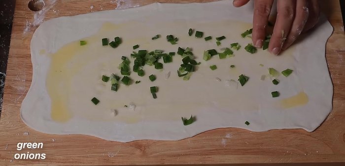 Sprinkle crushed green onions on top of the buttered dough.