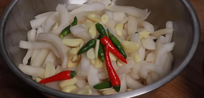 In a bowl, combine the drained radish, garlic, chili (optional), and sugar. Do not boil the vinegar and sugar mixture; mix the sugar directly into the radish for a crispier result. (280.3)