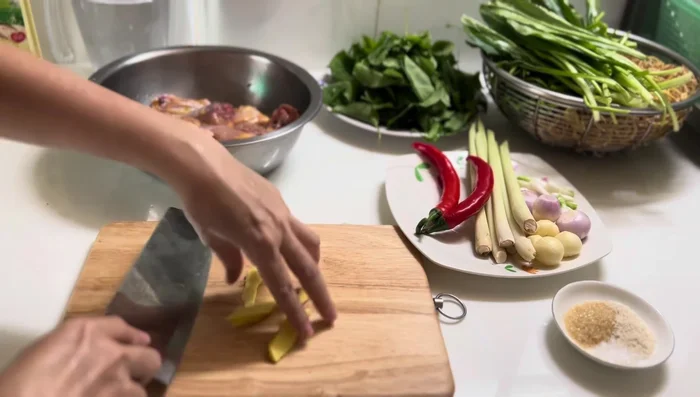 Prepare ingredients: slice ginger, chili, lemongrass, mince garlic, and chop other vegetables.