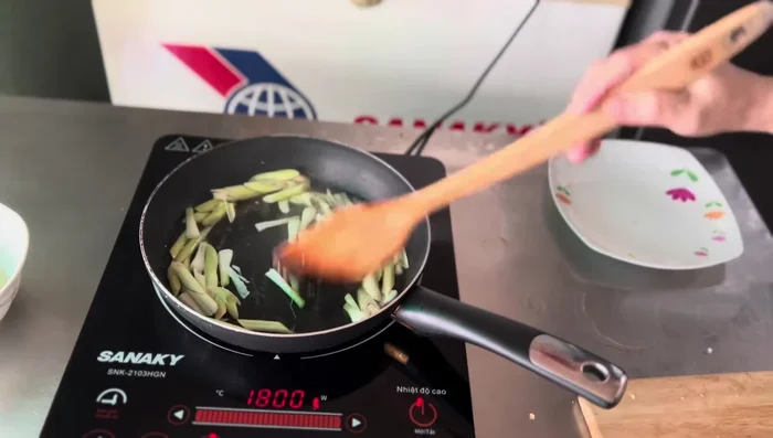 Using the reserved garlic oil, sauté lemongrass and green onion roots until fragrant.