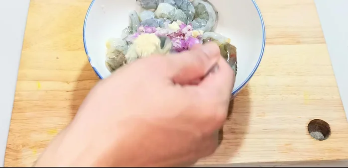 Marinate the shrimp with shallots, garlic, 1/2 tsp seasoning powder, 1/2 tsp MSG, 1/2 tsp ground pepper, and 1 tsp fish sauce. Cut the shrimp in half (optional, for shorter pieces). Marinate for 20 minutes.